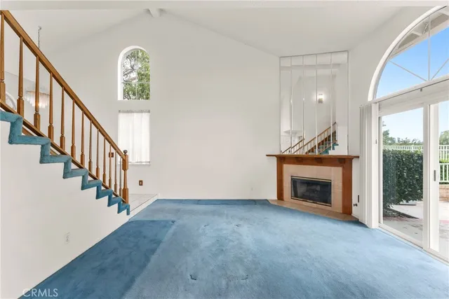 a view of an empty room with wooden floor fireplace and a window