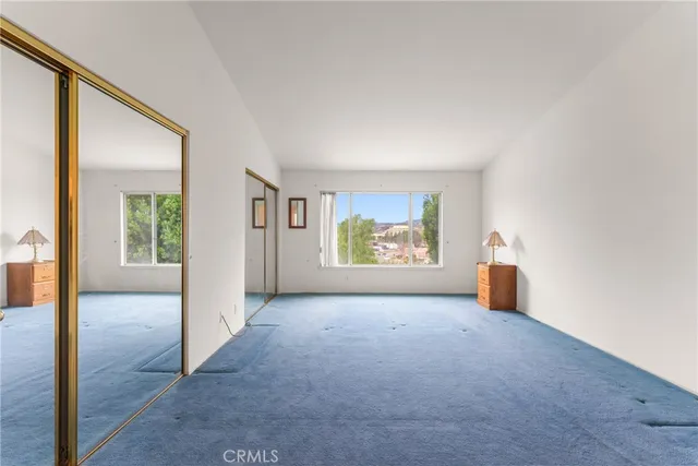 an empty room with windows and way to kitchen