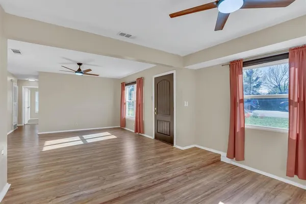 a view of an empty room with window and wooden floor