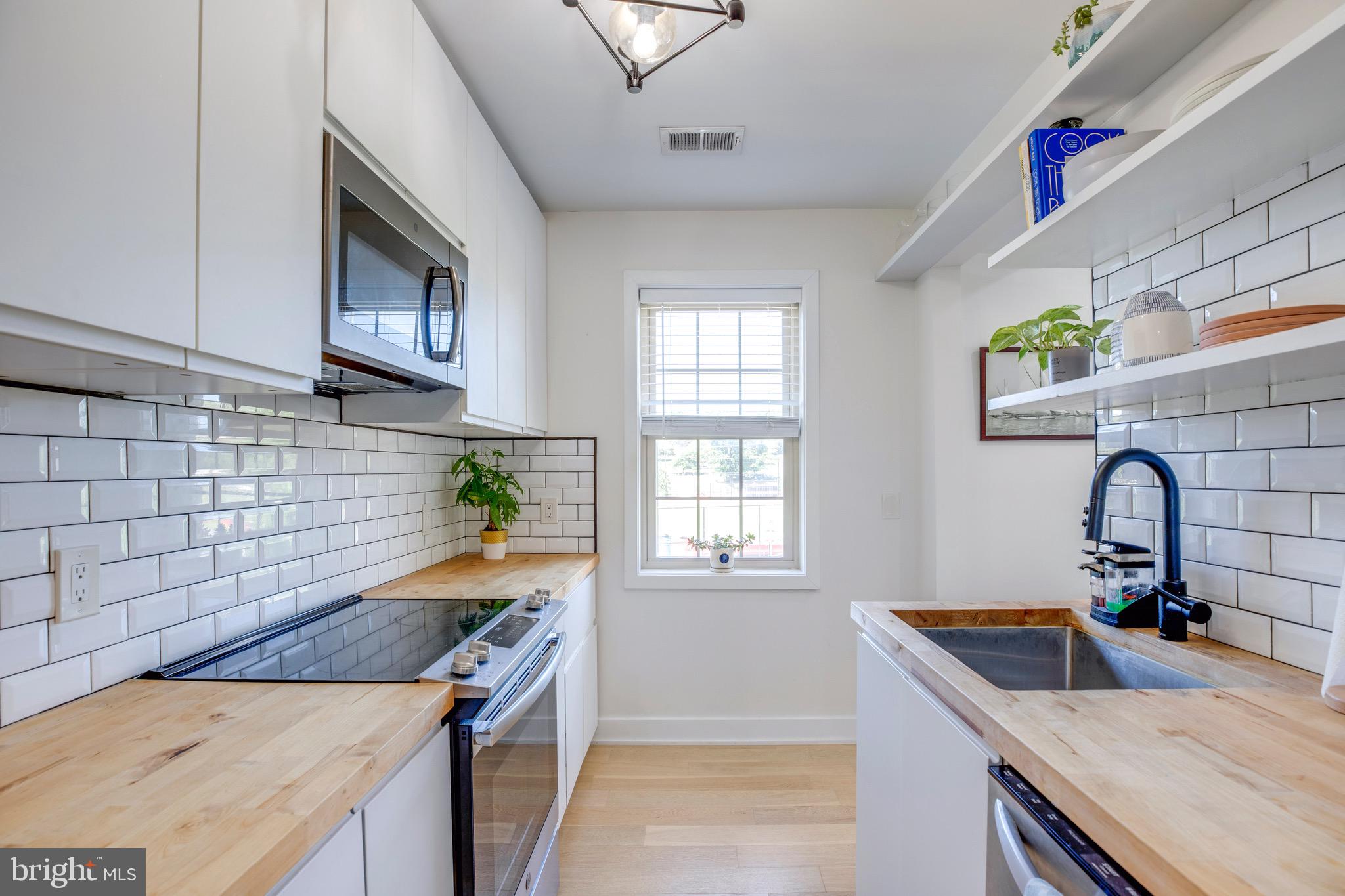 2625 3rd Street Northeast, Unit 203 Washington, DC 20002 - Photo 4 of 25 a kitchen with a sink a stove cabinets and a window