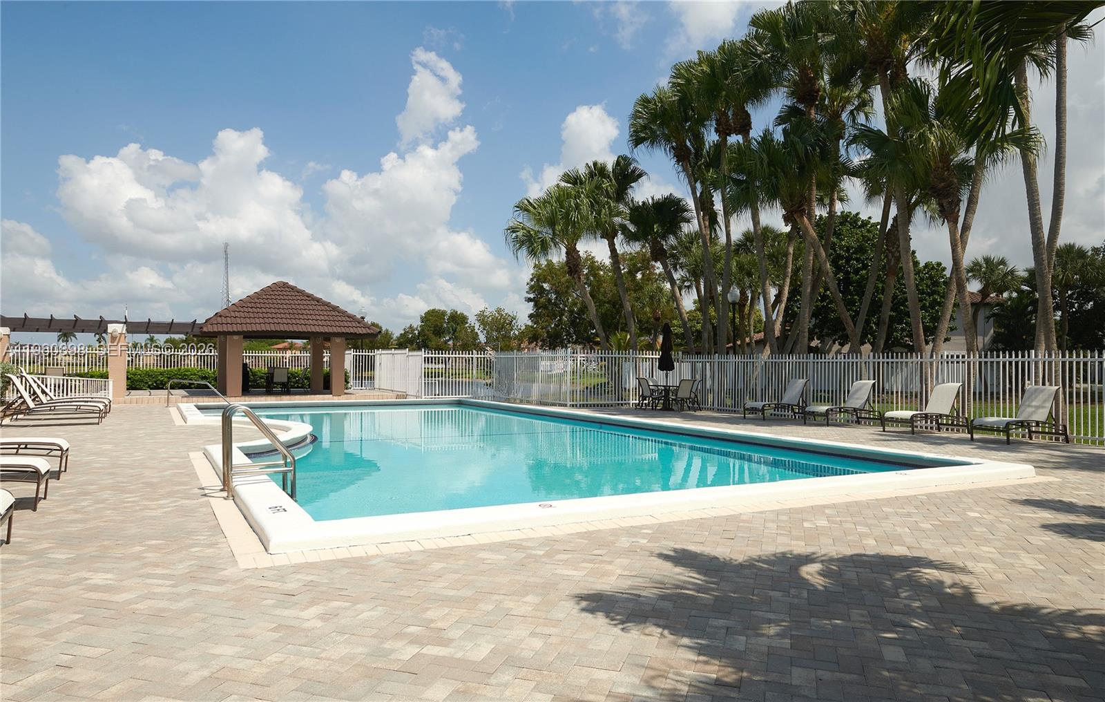 20030 Northwest 83rd Court Hialeah, FL 33015 - Photo 29 of 33 a view of a swimming pool with a lawn chairs under an umbrella