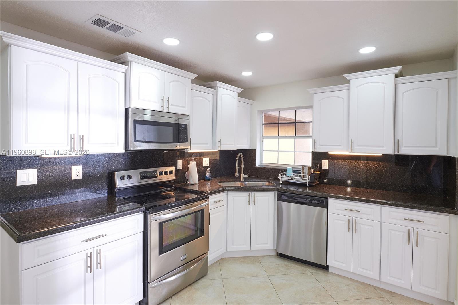 20030 Northwest 83rd Court Hialeah, FL 33015 - Photo 7 of 33 a kitchen with granite countertop white cabinets sink and stainless steel appliances