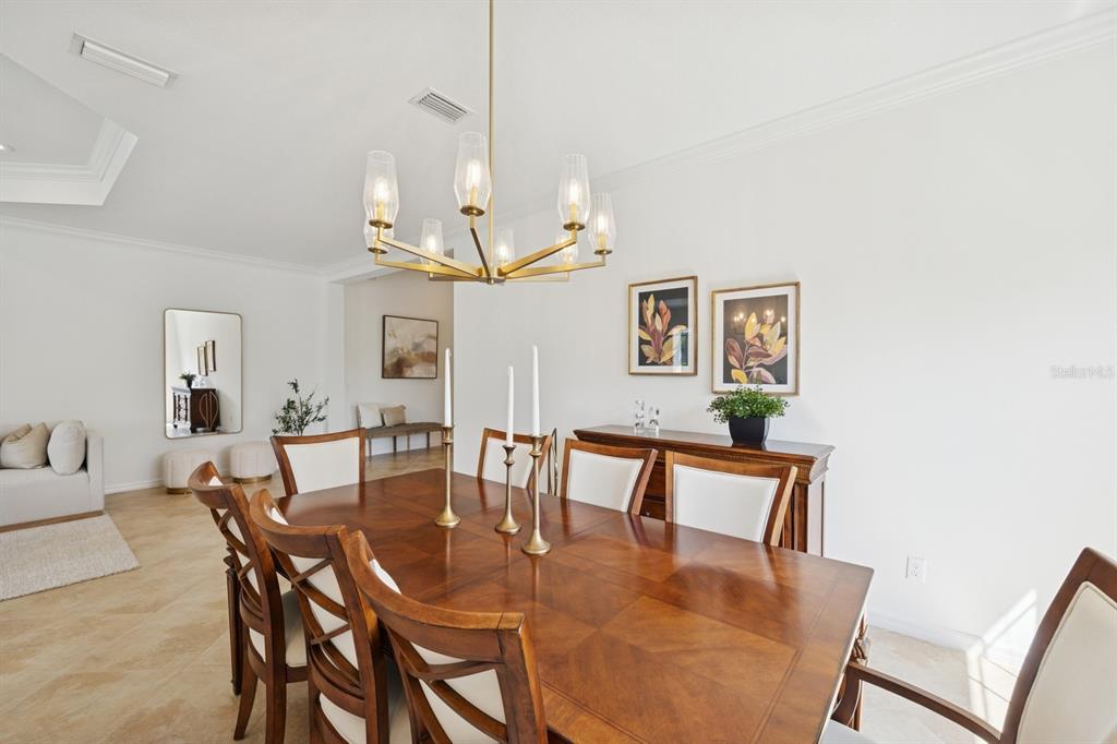 14614 Newtonmore Lane Lakewood Ranch, FL 34202 - Photo 13 of 72 a dining room with wooden floor a chandelier a wooden table and chairs