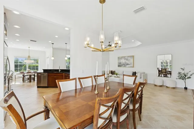 a kitchen with stainless steel appliances kitchen island granite countertop a stove a refrigerator a sink a dining table and chairs with wooden floor