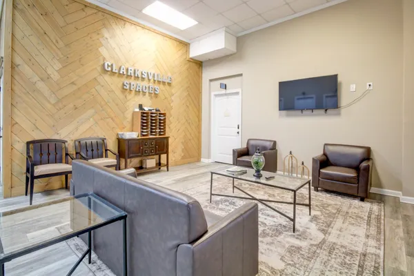 a living room with furniture a rug and wall paintings