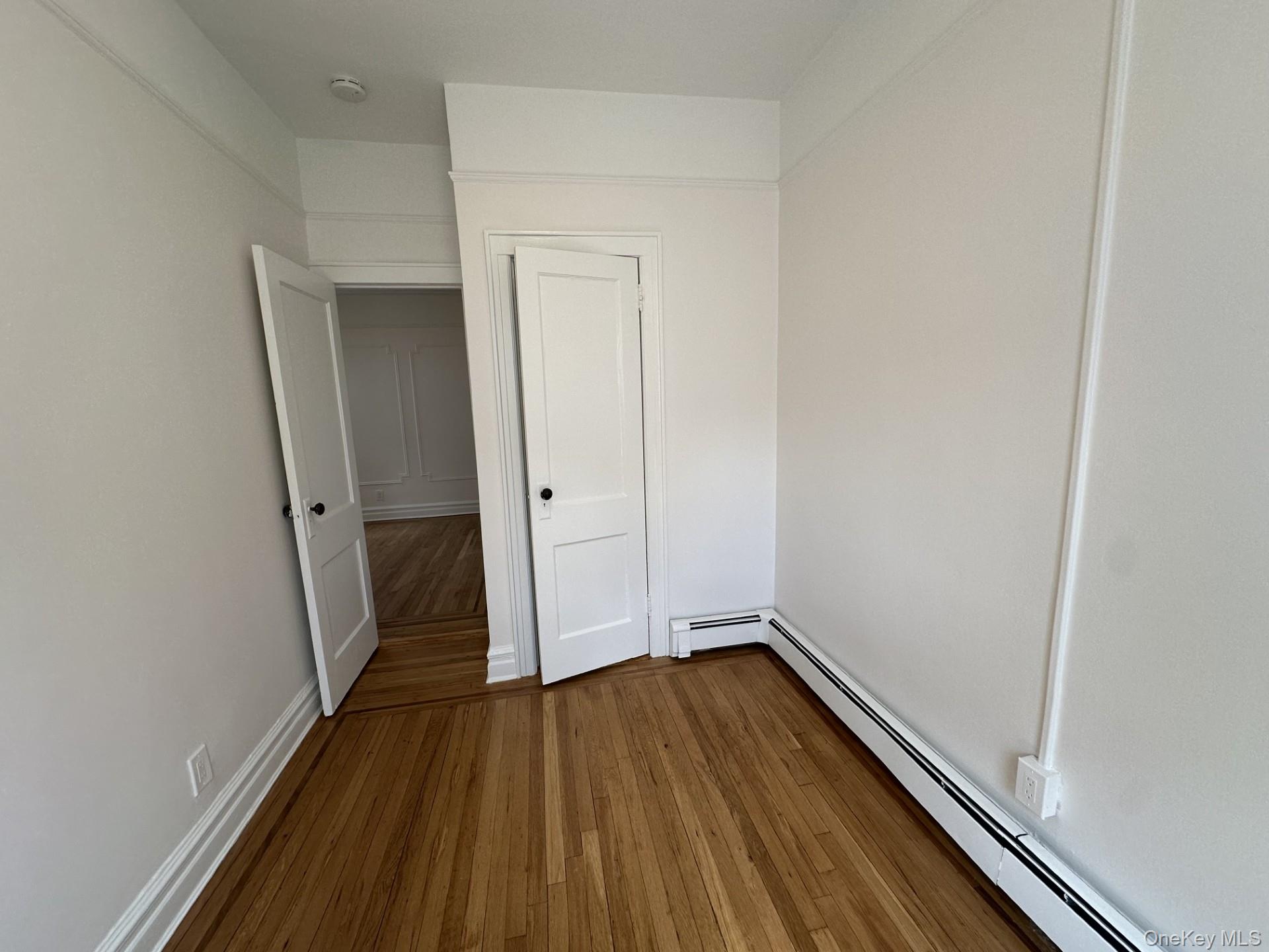 117 Plandome Road, Unit 2R Manhasset, NY 11030 - Photo 11 of 13 Second bedroom featuring a baseboard heating unit, hard wood floors, and a closet