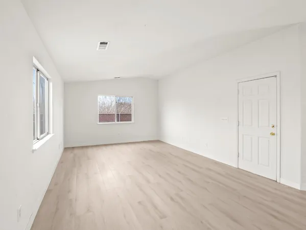 a view of a big room with wooden floor and windows