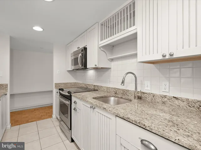 a kitchen with granite countertop a sink stainless steel appliances and cabinets