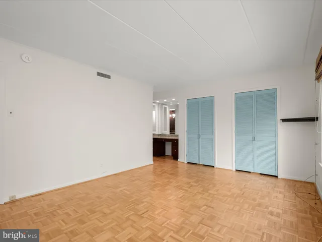 a view of an empty room with kitchen and a window