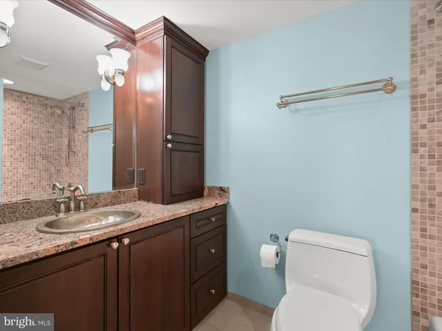 a bathroom with a granite countertop toilet sink and mirror