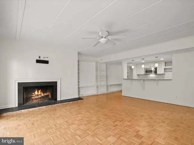 a view of empty room with kitchen and fireplace