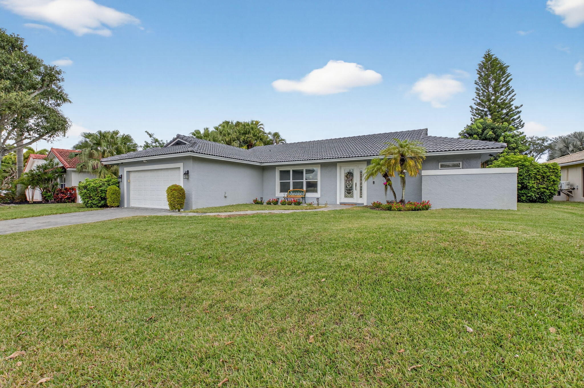 10302 Crosswind Road Boca Raton, FL 33498 - Photo 2 of 27 a white house that has a big yard with wooden fence