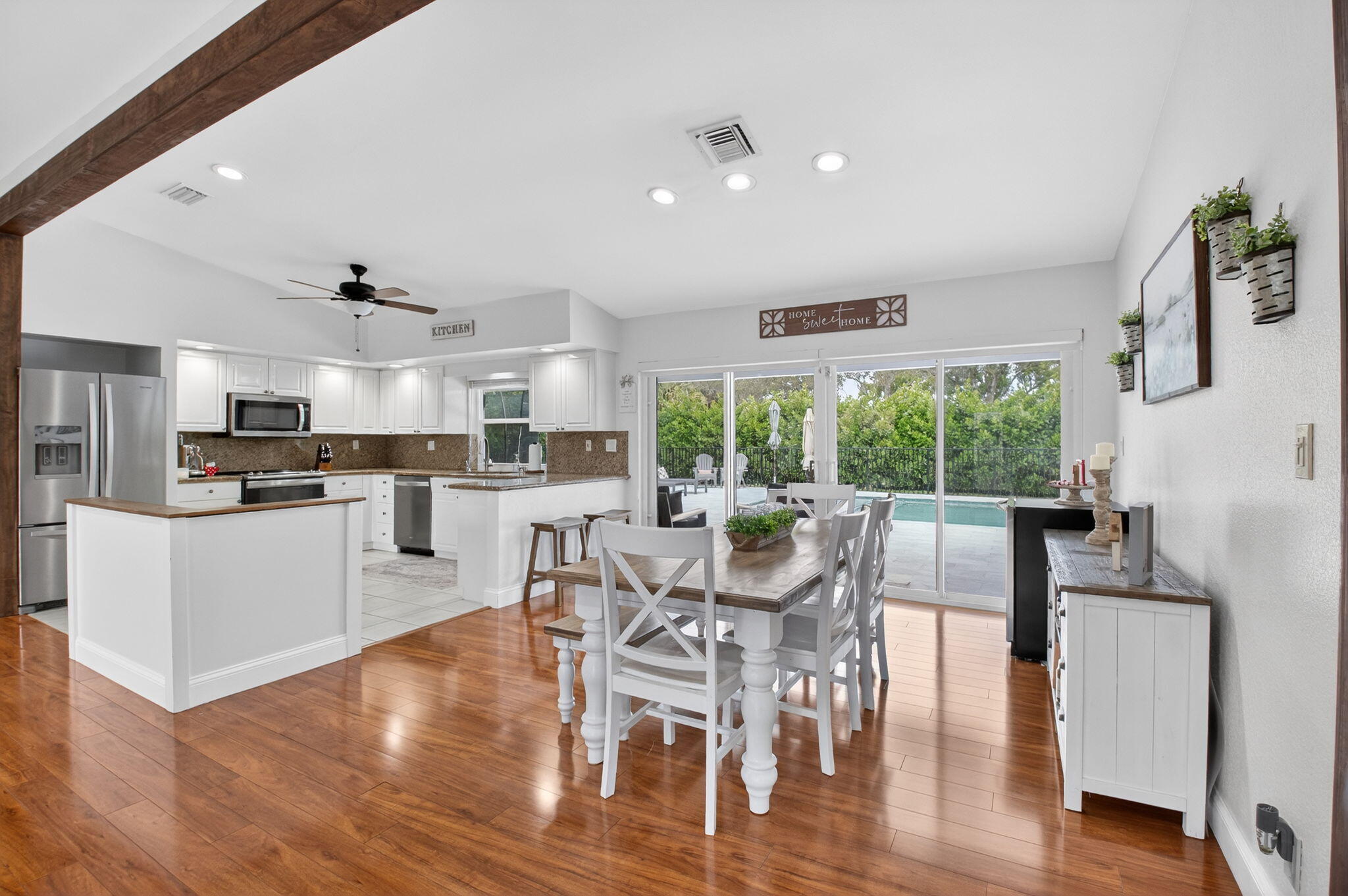 10302 Crosswind Road Boca Raton, FL 33498 - Photo 4 of 27 a kitchen with stainless steel appliances granite countertop a stove top oven a sink dishwasher a dining table and chairs with wooden floor