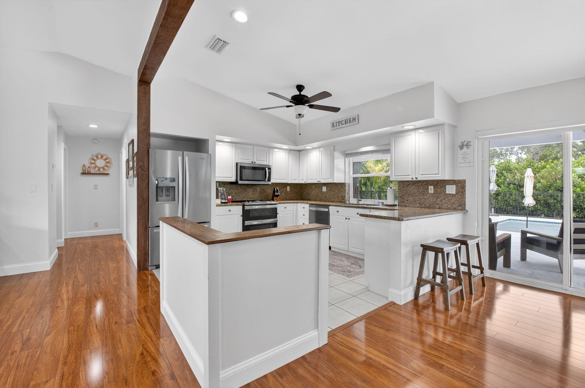 10302 Crosswind Road Boca Raton, FL 33498 - Photo 6 of 27 a kitchen with stainless steel appliances a dining table chairs stove and white cabinets