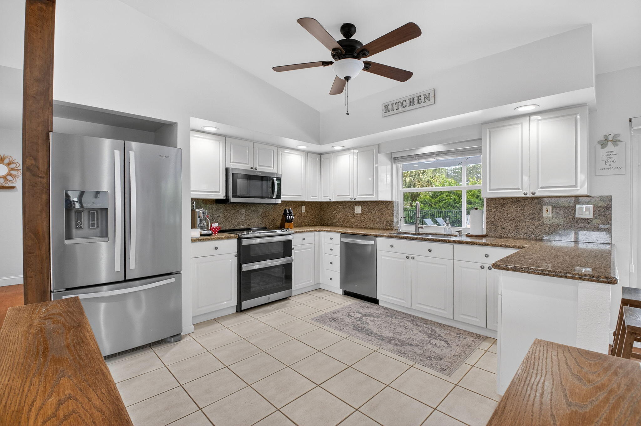 10302 Crosswind Road Boca Raton, FL 33498 - Photo 7 of 27 a kitchen with granite countertop a refrigerator a sink a stove a microwave a counter top space and cabinets