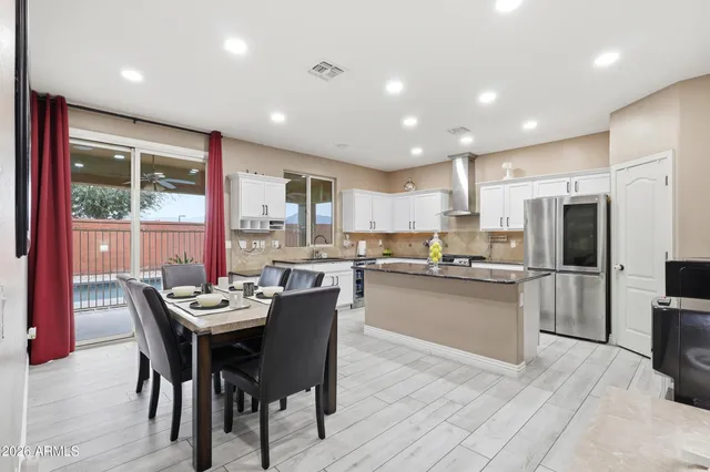 a kitchen with kitchen island granite countertop a stove top oven a sink dishwasher a refrigerator and cabinets with wooden floor