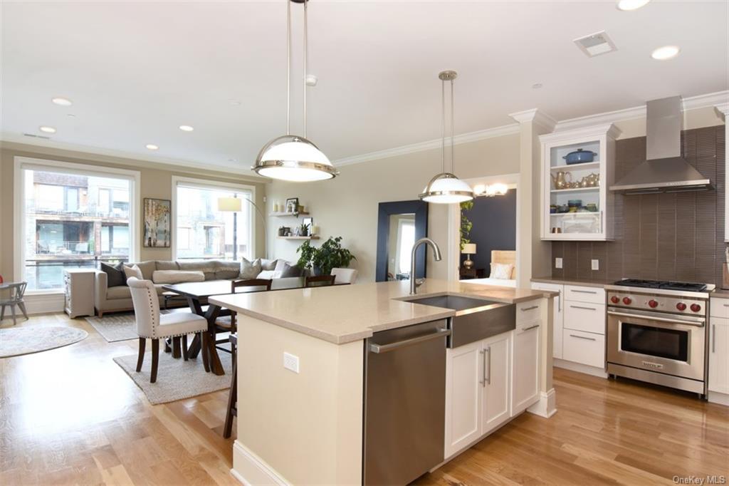 a kitchen with kitchen island granite countertop a stove a sink a dining table and chairs with wooden floor