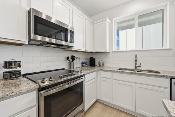a kitchen with stainless steel appliances granite countertop white cabinets and a stove top oven