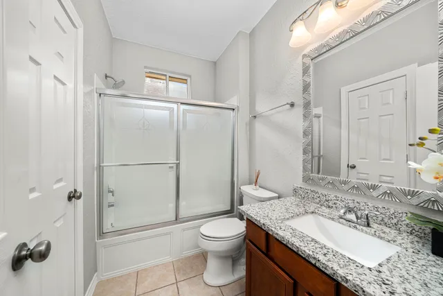 a bathroom with a granite countertop sink toilet a mirror a shower and a vanity