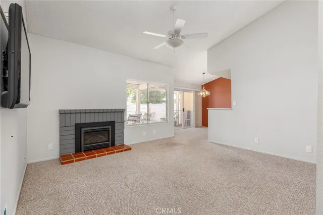 an empty room with fireplace fan and windows