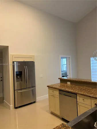 a kitchen with granite countertop a refrigerator and a sink