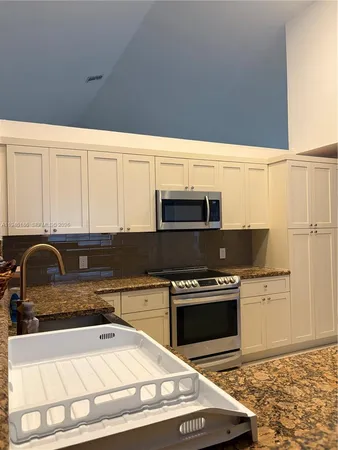 a kitchen with granite countertop a stove a sink and a microwave