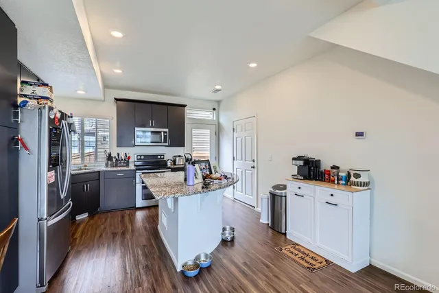 a kitchen with a sink wooden floor and stainless steel appliances