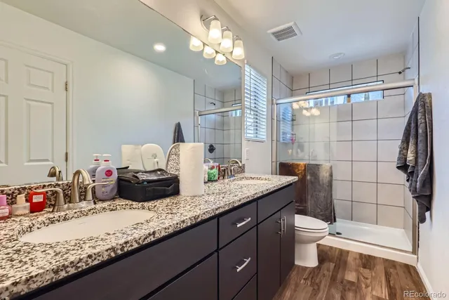 a bathroom with a granite countertop sink a toilet and shower