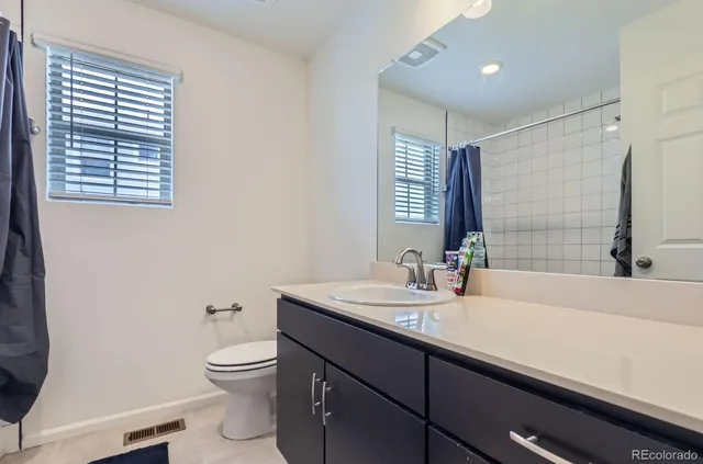 a bathroom with a sink a toilet a mirror and window