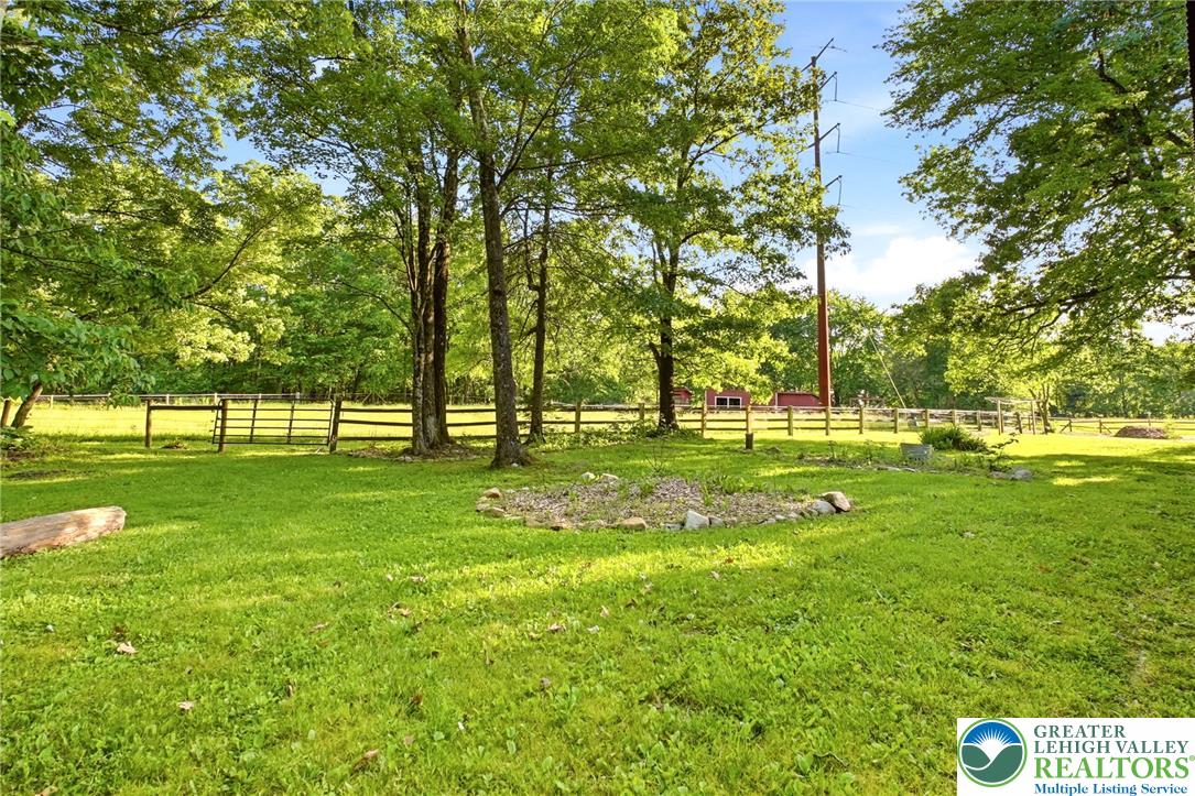 9033 Loop Road Slatington, PA 18080 - Photo 37 of 53 A verdant, open field extends towards distant trees, framed by a classic wooden fence.