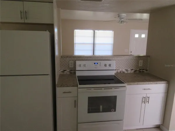 a view of a kitchen with a stove refrigerator and window