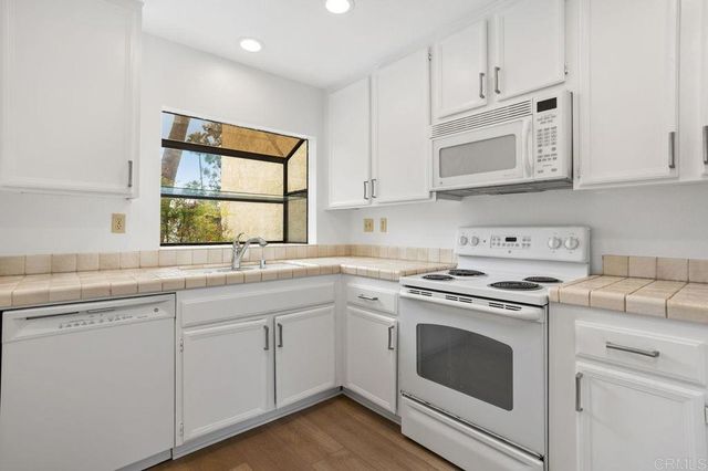 a kitchen with cabinets appliances a sink and a window