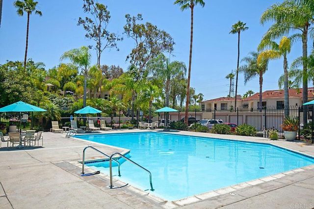 a view of a swimming pool with a lawn chairs under an umbrella