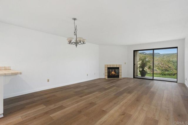 an empty room with wooden floor fireplace and windows