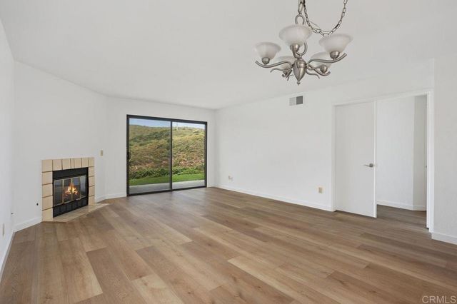 a view of an empty room with wooden floor fireplace and a window