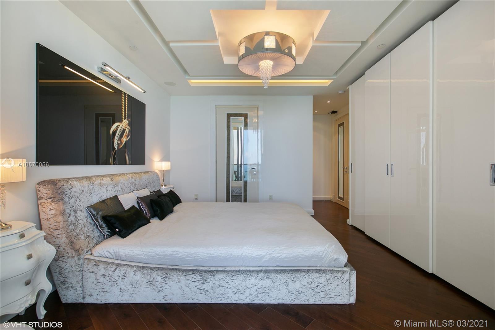 9703 Collins Avenue, Unit PH07 Bal Harbour, FL 33154 - Photo 13 of 23 a bedroom with a large bed and a chandelier