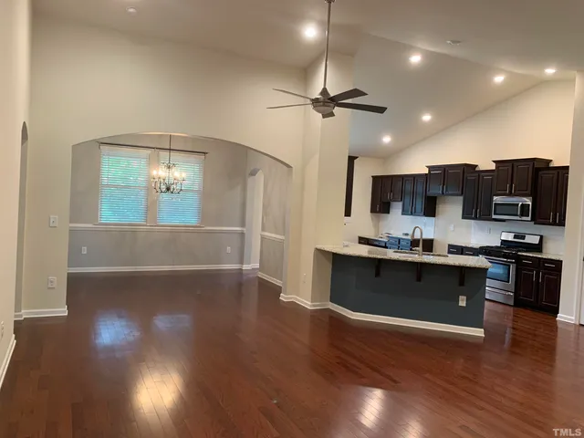 a kitchen with stainless steel appliances granite countertop a stove top oven a sink dishwasher and a refrigerator with wooden floor