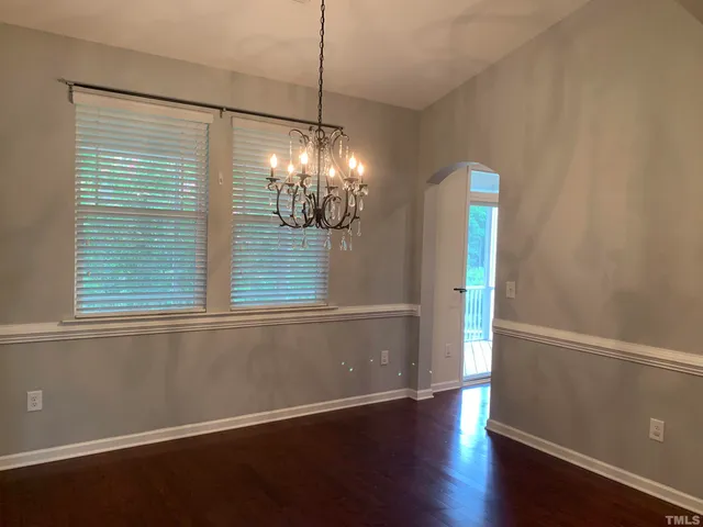 a view of an empty room with wooden floor fireplace and a window