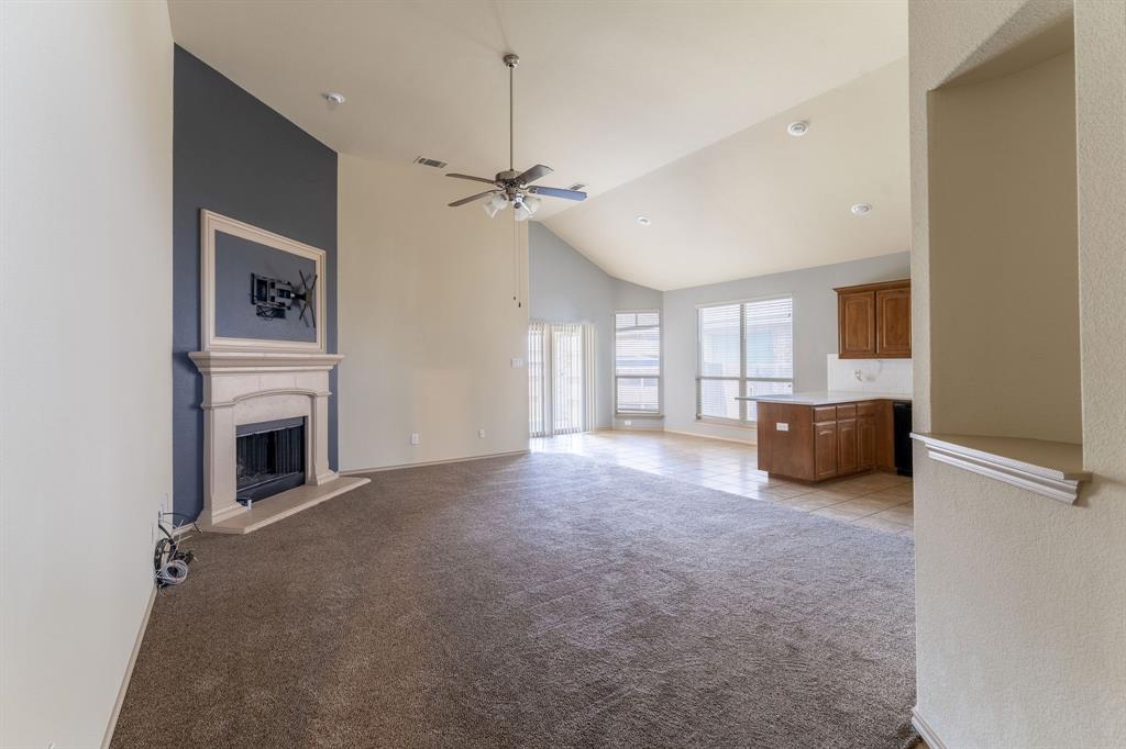 11156 Hawks Landing Road Fort Worth, TX 76052 - Photo 5 of 30 Spacious living area featuring a stone mantel fireplace, vaulted ceilings, and a ceiling fan