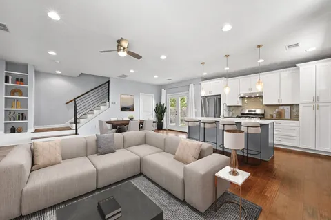 a kitchen with stainless steel appliances kitchen island granite countertop a sink a stove a refrigerator and white cabinets with wooden floor