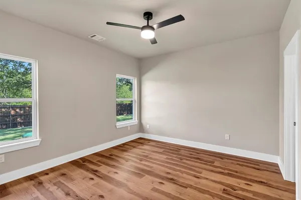 a view of empty room with wooden floor and fan