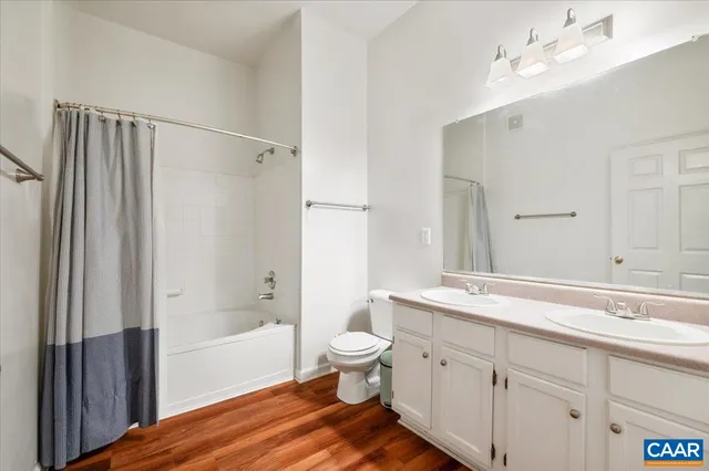 a spacious bathroom with a double vanity sink a toilet a shower and a mirror