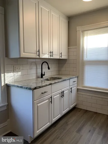 a kitchen with granite countertop white cabinets and sink