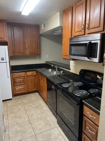 a kitchen with stainless steel appliances granite countertop a stove a sink and a microwave