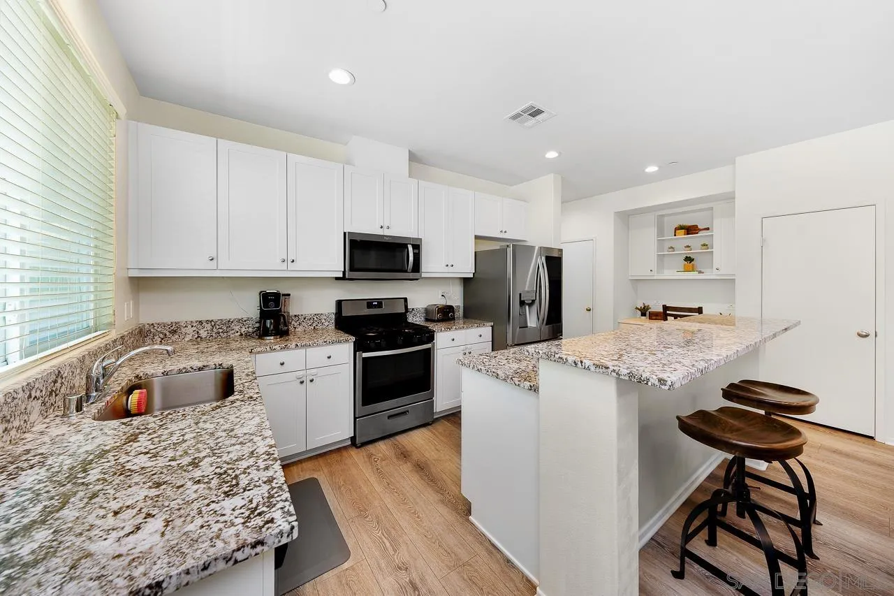 1290 Santa Victoria Road, Unit 2 Chula Vista, CA 91913 - Photo 9 of 41 a kitchen with stainless steel appliances kitchen island granite countertop a sink dishwasher a stove refrigerator and microwave with wooden floor