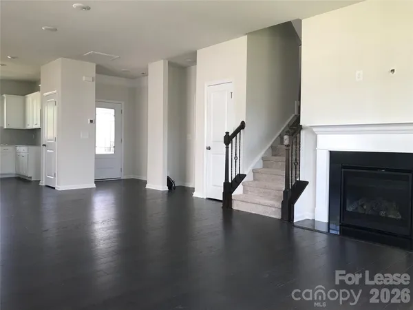 a view of an empty room with wooden floor and a fireplace