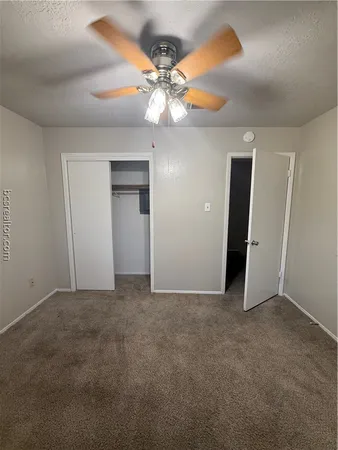 an empty room with closet and a chandelier fan