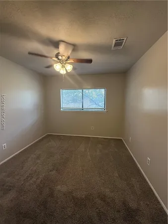 an empty room with a window and a ceiling fan