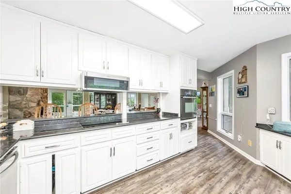 a kitchen with granite countertop white cabinets and white appliances