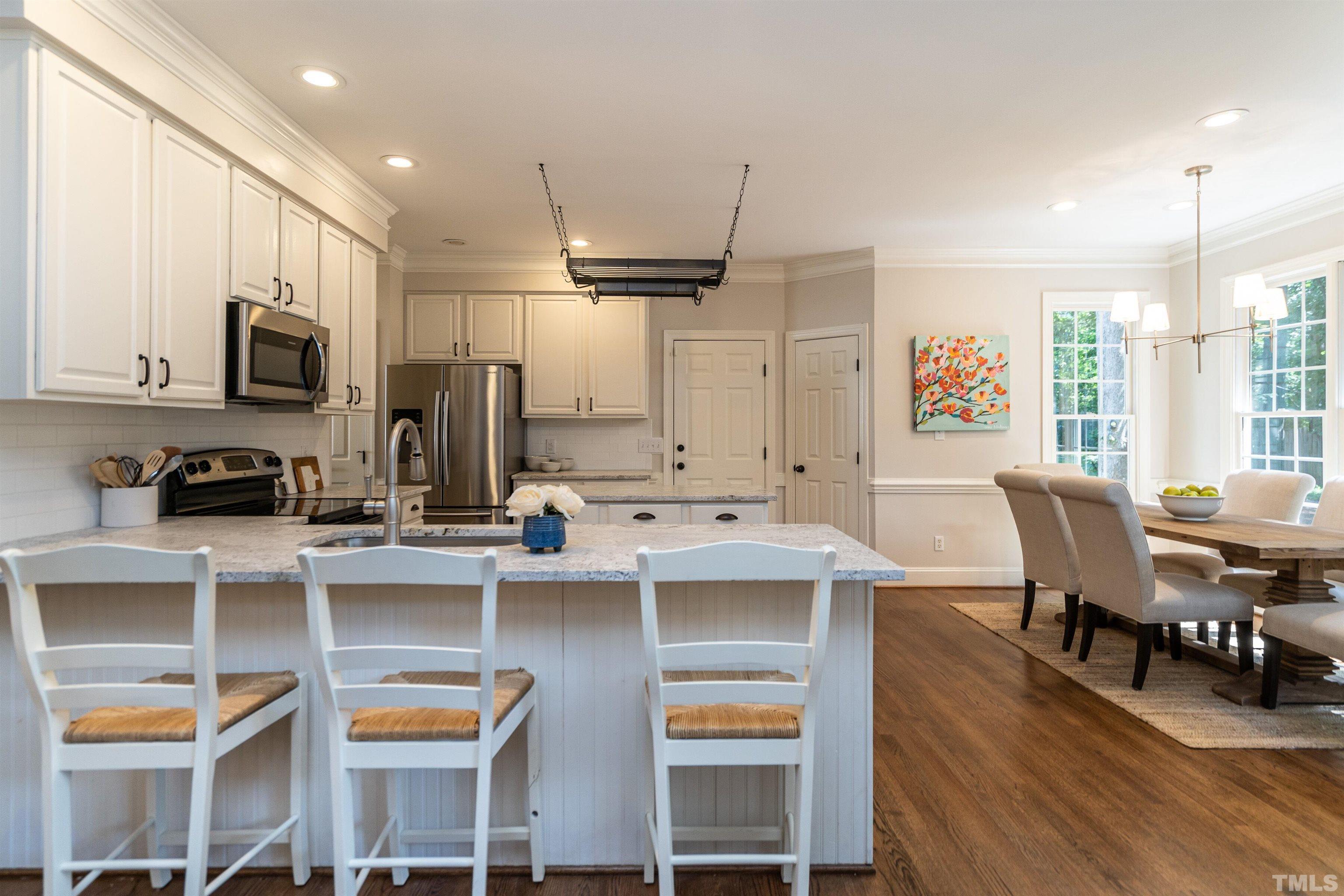 3016 Stone Gap Court Raleigh, NC 27612 - Photo 12 of 37 a kitchen with stainless steel appliances a dining table chairs and a refrigerator